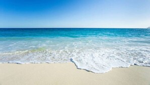 Une plage à l’eau d’un bleu limpide et au rivage sablonneux.