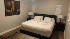 Ein Schlafzimmer mit einem Bett, zwei Nachttischen, einem Deckenventilator und einem Bild an der Wand.