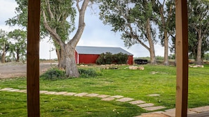 A red barn with a black truck parked nearby, surrounded by a grassy area with stone stepping stones and large trees. - New modern farm house on the Still Water Ranch. (Montrose)