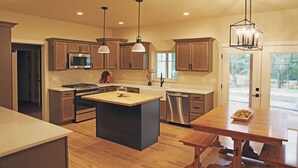 A modern kitchen with wooden cabinets, stainless steel appliances, and a central island. - New modern farm house on the Still Water Ranch. (Montrose)
