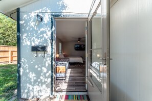 Un camping-car moderne doté d’une chambre à coucher comprenant un lit, un ventilateur de plafond et un téléviseur.