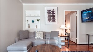 Una sala de estar moderna con un sofá seccional gris, una mesa de centro de madera y un televisor montado.