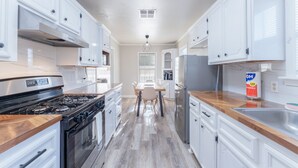 Una cocina moderna con armarios blancos, una estufa de acero inoxidable y una encimera de madera.