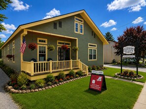 A two-story house with a porch, a small garden, and a sign indicating office hours.