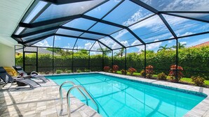 Une piscine dotée d’une enceinte en verre, entourée de chaises longues et d’une terrasse carrelée.