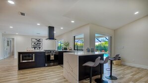 Une cuisine moderne dotée d’un îlot central, de tabourets de bar et offrant une vue sur l’extérieur.