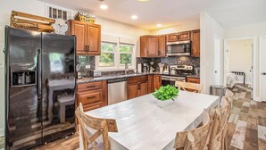 A modern kitchen with stainless steel appliances, wooden cabinets, and a central island with chairs.