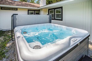 A hot tub in a backyard with a white exterior wall and windows. - Secluded Pool Playhouse: Hot Tub, Game Room, Fire Pit (New Buffalo)