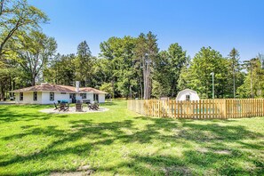 Une maison avec un jardin clôturé, une terrasse avec des meubles d’extérieur et un petit abri de jardin.