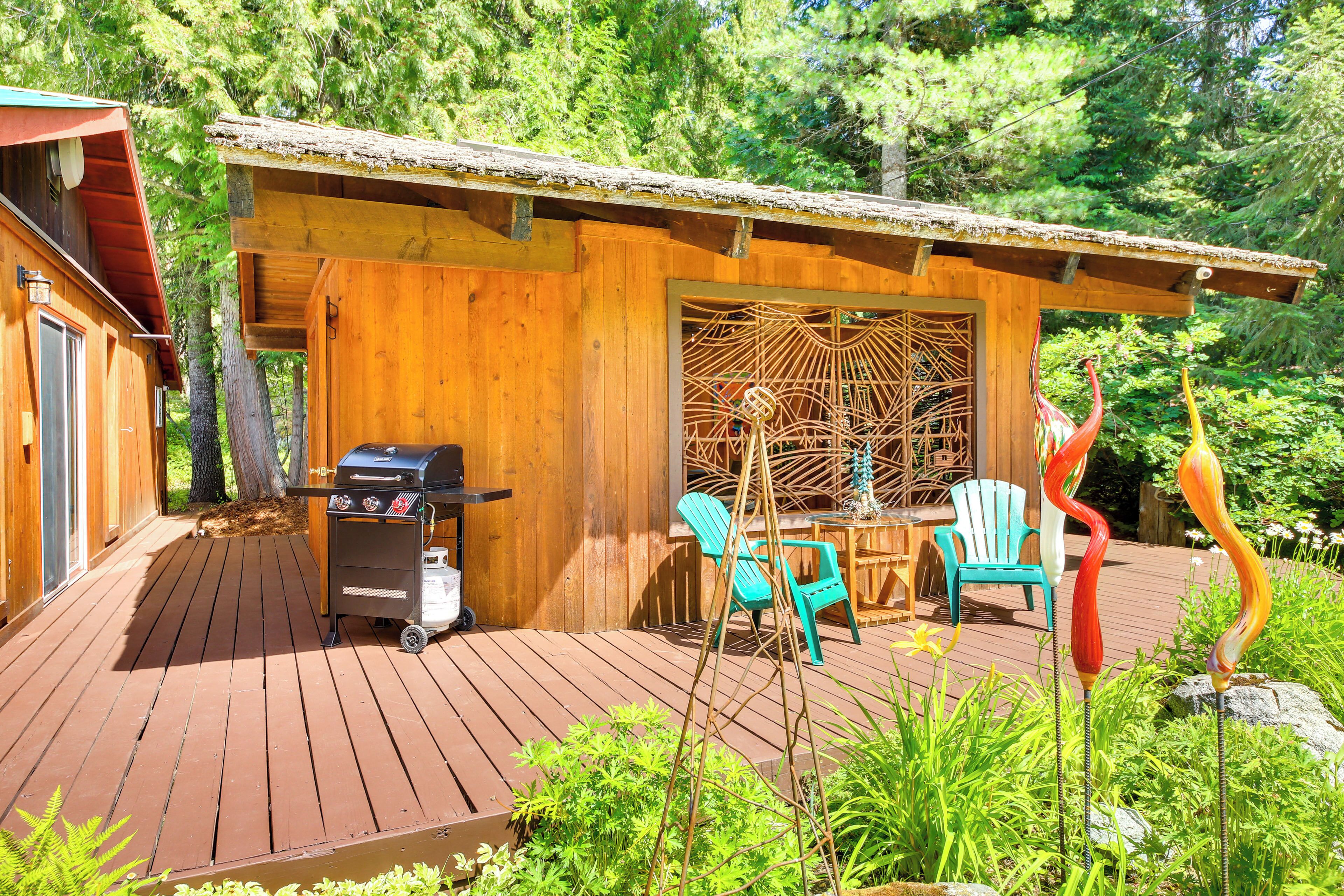 A wooden cabin with a deck, a grill, and outdoor chairs.