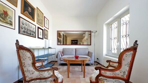 Una habitación con sofá, dos sillones, una mesa y un espejo.