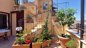 Una terraza en la azotea con plantas en macetas, una escalera y un mural.