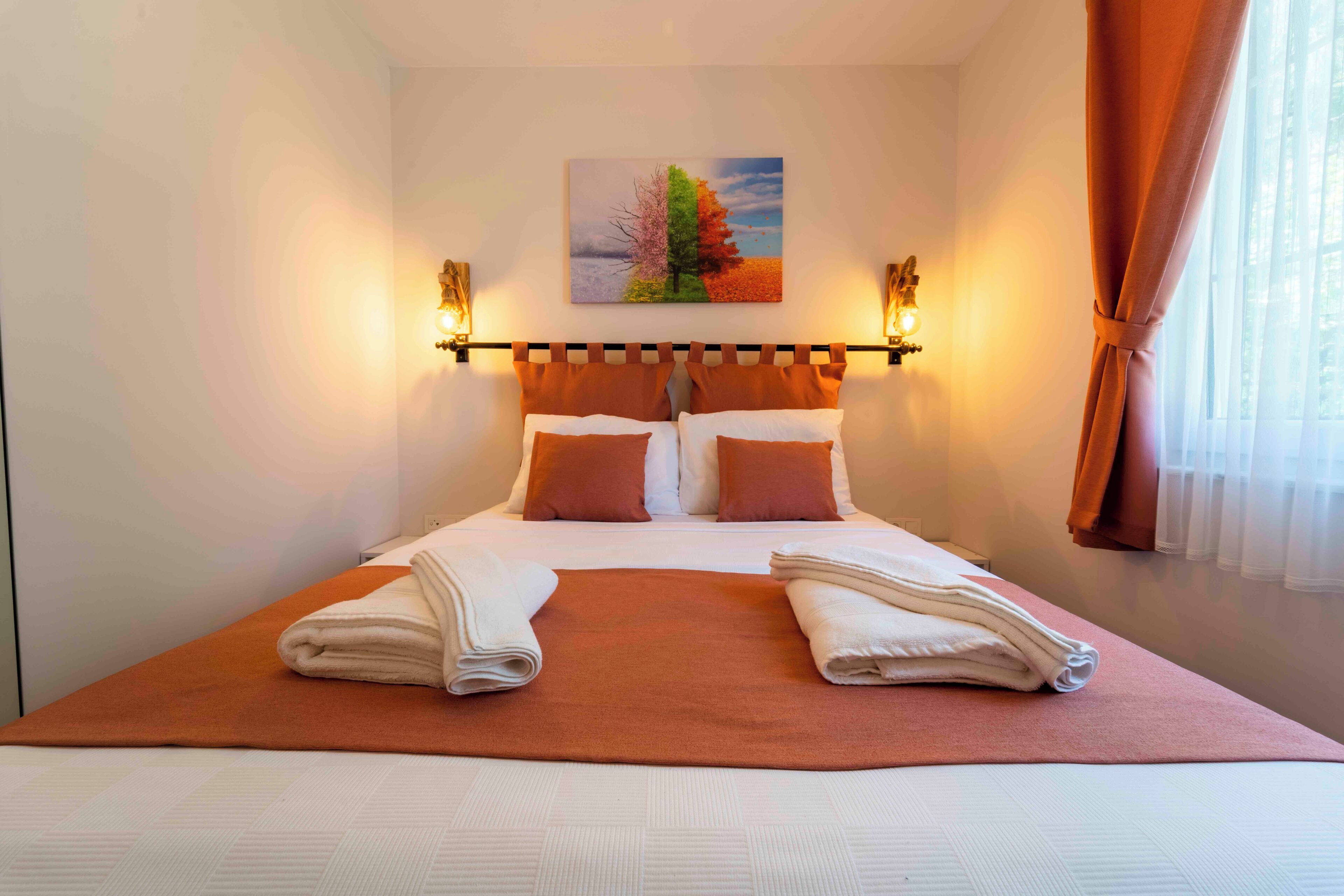 A neatly made bed with a brown bedspread, white pillows, and two folded towels.