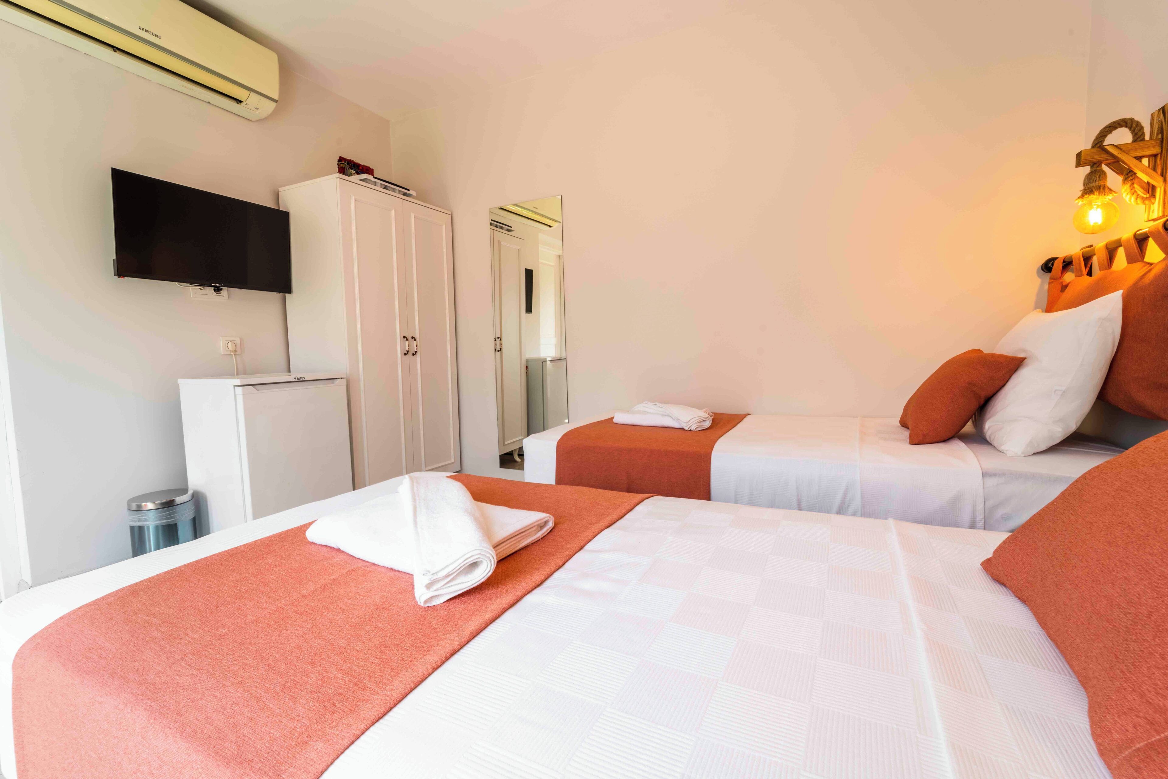 A hotel room with two beds, a TV, a wardrobe, and a trash bin.