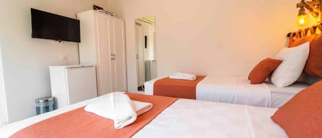 A hotel room with two beds, a TV, a wardrobe, and a trash bin.