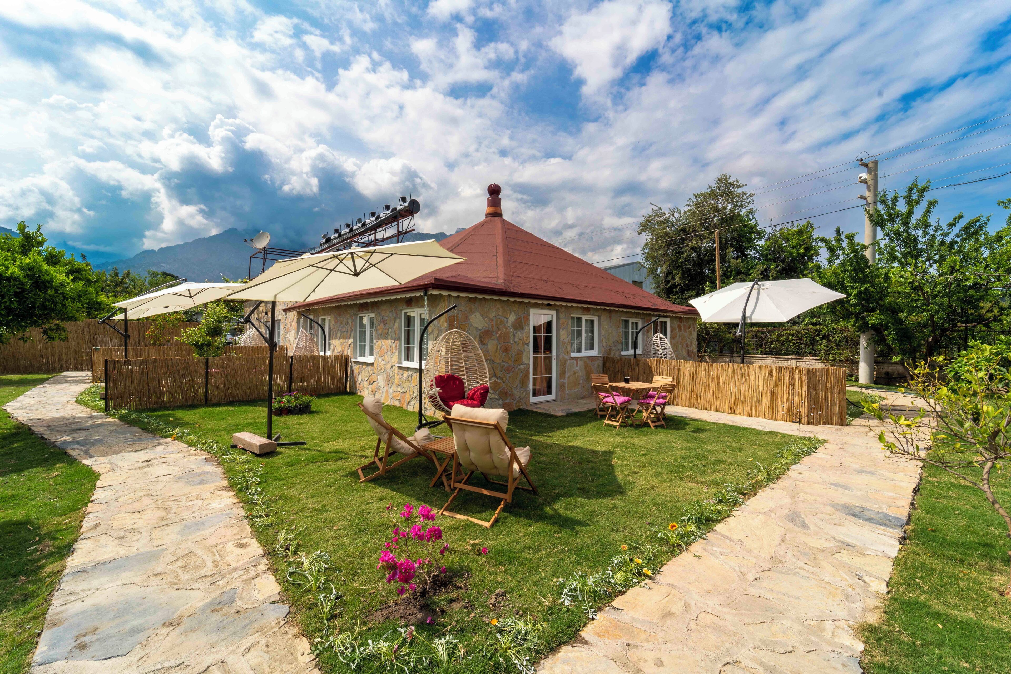 Une maison avec un chemin de pierre menant à un patio aménagé avec du mobilier d’extérieur et une antenne parabolique.