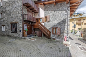 Un bâtiment en pierre doté d’un escalier en bois, de balcons et d’un sol pavé.