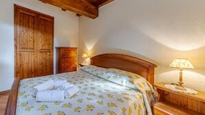 Une chambre à coucher avec un lit en bois, une table de chevet avec une lampe, une commode et une armoire.