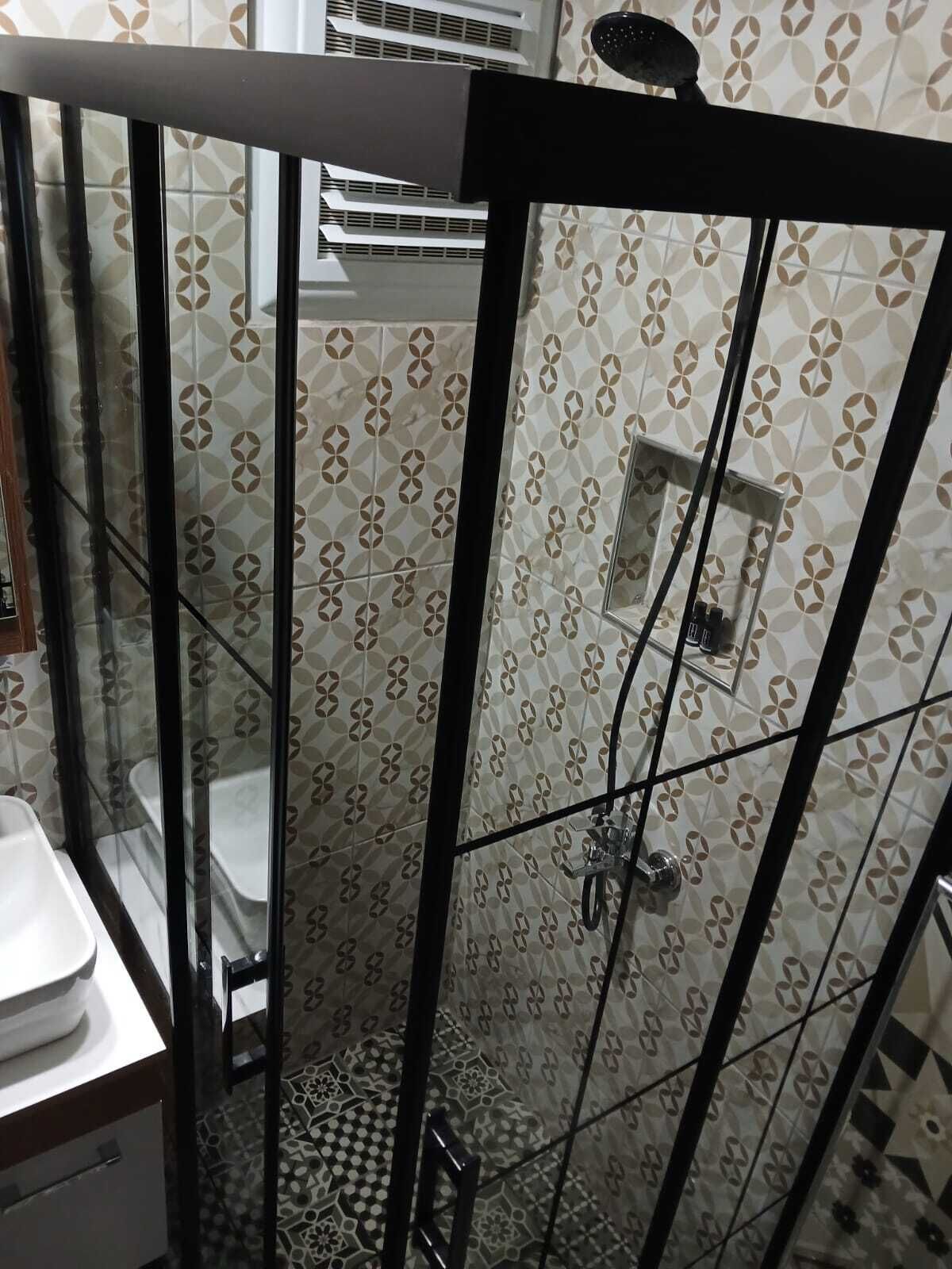 A bathroom with a glass-enclosed shower, a toilet, and a sink.
