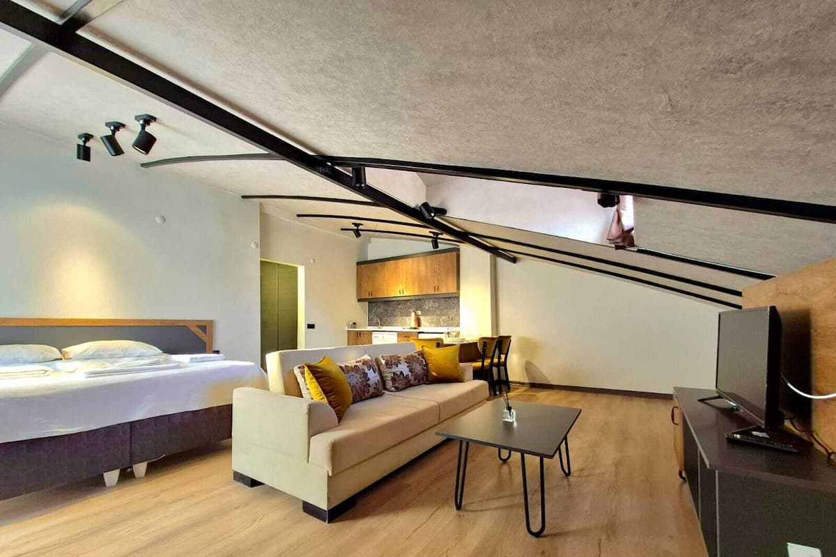 Ein kompakter Wohnraum mit Bett, Sofa und einem kleinen Tisch.