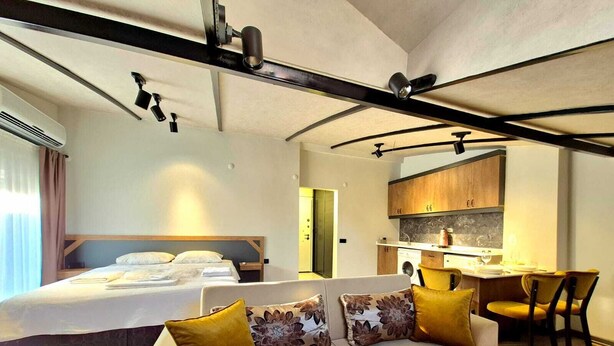 Een moderne hotelkamer met een bed, een bank, een eethoek en een keuken.