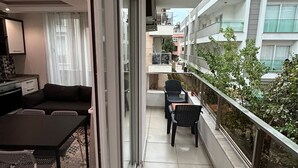 Een balkon met een eethoek, inclusief een tafel en stoelen, en uitzicht op de stads skyline.