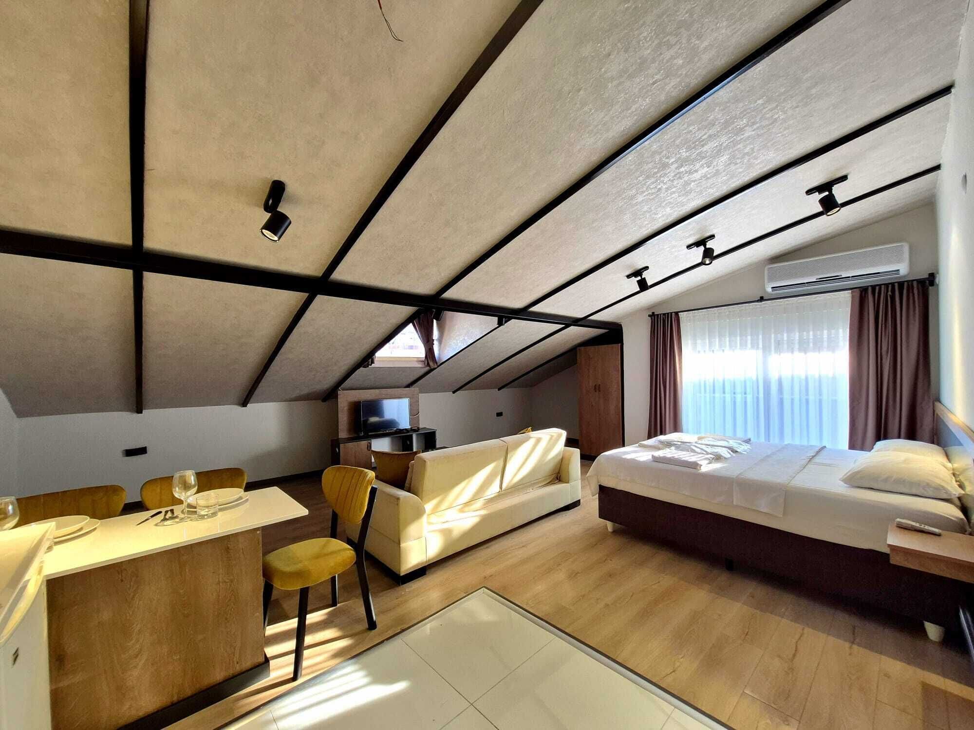 Una habitación de hotel moderna con cama, sofá, zona de comedor y televisión.