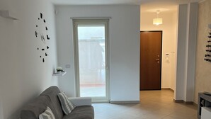 Ein modernes Wohnzimmer mit einer Couch, einem Couchtisch und einer Tür, die auf einen Balkon führt.