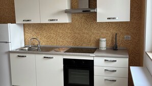 Eine moderne Küche mit weißen Schränken, einem eingebauten Ofen und einer gefliesten Spritzschutzwand.