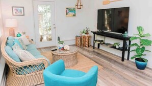 A living room with a sofa, a blue armchair, a TV, and a coffee table. - Cottage on River (Jacksonville)