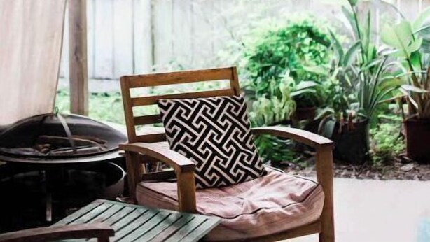 A covered outdoor seating area with wooden furniture, string lights, and potted plants. - Cottage on River (Jacksonville)