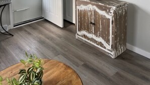 Una stanza con una porta bianca, una televisione appesa al muro e un mobiletto in legno rustico.