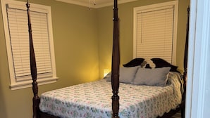 Una cama con dosel con colcha estampada, un ventilador de techo y una luz nocturna.