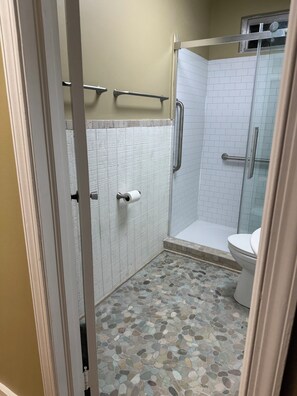A bathroom with a shower, toilet, and a handrail. - Entire House - Antique Mall Cottage (Summerville)
