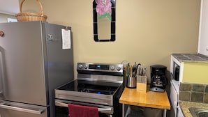 Una cocina con un refrigerador de acero inoxidable, horno, cafetera y tostadora.