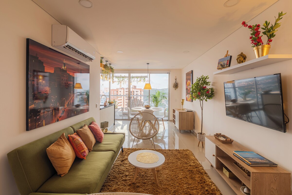 Uma sala de estar moderna com um sofá verde, uma mesa de centro redonda e uma TV de tela plana na parede.