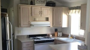 Una cocina con armarios de color claro, un refrigerador de acero inoxidable, una estufa a gas y un lavamanos.