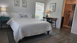 Ein Schlafzimmer mit einem großen Bett, einem Nachttisch, einem Schreibtisch und einer Duschkabine.
