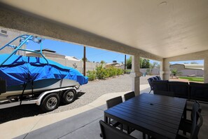 Un patio couvert avec une table et des chaises, un abri pour bateau et une vue sur un quartier résidentiel.