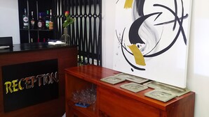 A reception desk with a 'RECEPTION' sign, a black decorative partition, and a large abstract painting on the wall. - Villa des roses (Douala)