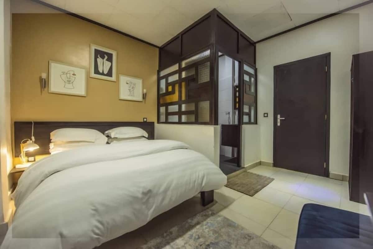 Ett hotellrum med en stor säng, en garderob, ett skrivbord och en dörr.