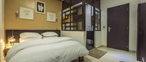 A hotel room with a large bed, a wardrobe, a desk, and a door.