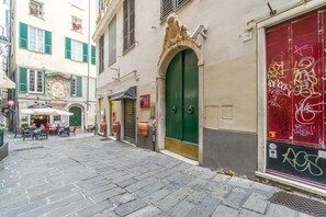 A narrow street with cobblestone pavement, a green door, and a red door with graffiti.