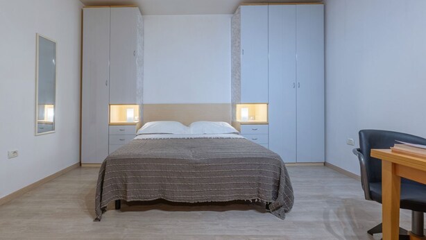 Un dormitorio con cama, mesitas de noche, escritorio y una silla.