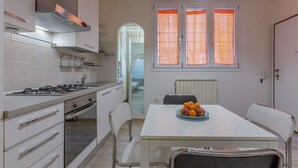 Una cocina moderna con armarios blancos, una estufa a gas y un comedor con mesa y sillas.