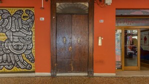 Entrada de un edificio con una puerta de madera grande, un mural en la pared y una tienda con un letrero.
