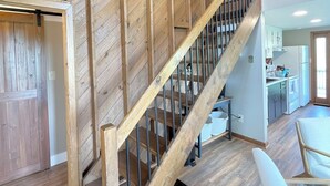 Una escalera de madera con barandilla de metal que lleva a una zona de cocina.