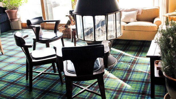 A cozy living room with a fireplace, plaid carpet, and comfortable seating.