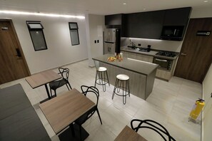 A modern kitchen with a central island, bar stools, and a dining table with chairs.