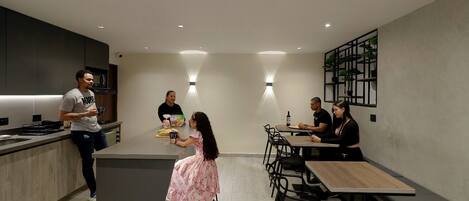 A modern kitchen with a central island, built-in appliances, and a seating area with tables and chairs.